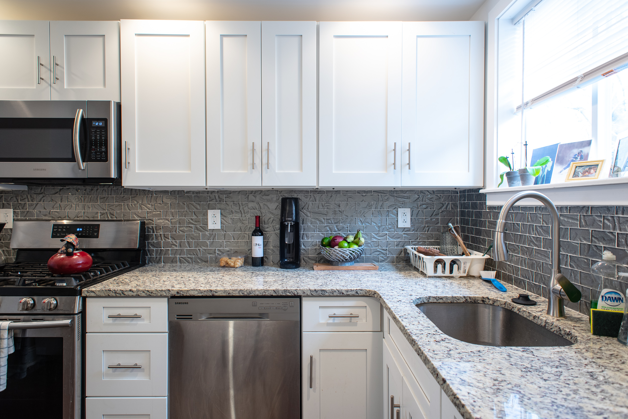 White Kitchen Cabinets with Marble Countertop and Tile Backsplash