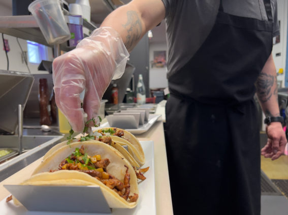 Salvador Zamuvio garnishes tacos with cilantro