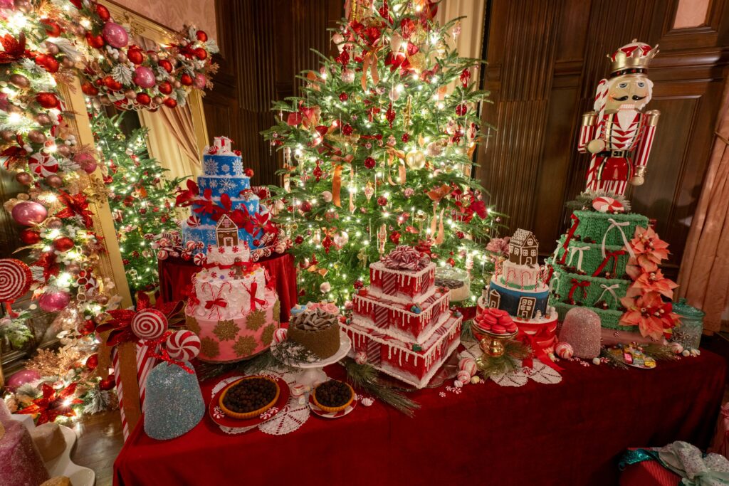 Blue Christmas trees light up the conservatory. The Peppermint Palace in the music room at Longwood Gardens features holiday decor like faux cakes, trees, garlands, and other decorations red and green decorations for the festive season. 